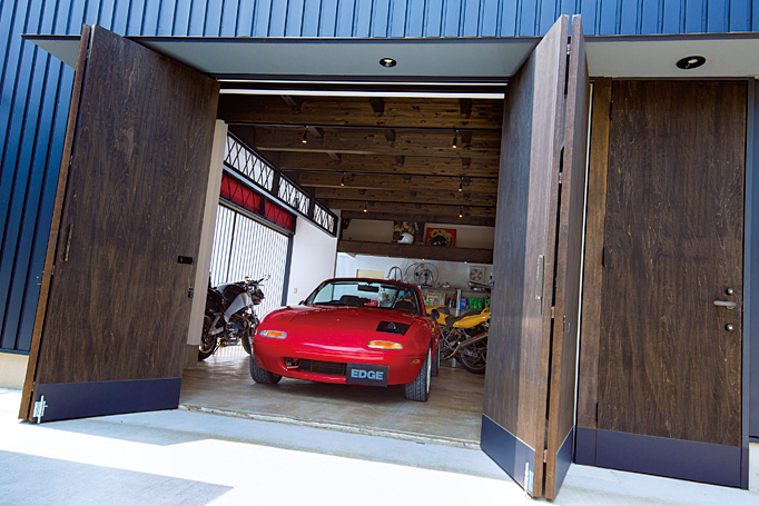 ▲右手のドアが玄関。ガレージの出入り口は、木製の折れ戸と格子状のスライドドアの2つ。ガレージドアにもこだわれば、閉じていても開いていても視覚的に絵になる