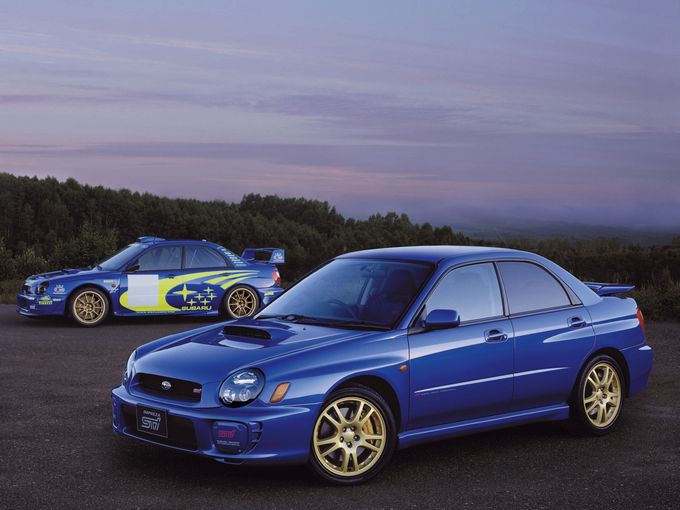 ▲2000年にデビューした2代目スバル インプレッサWRX。写真は「WRX STi」で、奥に写っているのは世界ラリー選手権を戦ったらWRカー（ワールドラリーカー）